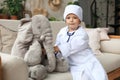 Adorable child dressed as doctor playing with toy elephant, checking its breath with stethoscope Royalty Free Stock Photo