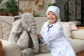 Adorable child dressed as doctor playing with toy elephant, checking its breath with stethoscope Royalty Free Stock Photo