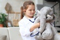 Adorable child dressed as doctor playing with toy elephant, checking its breath with stethoscope Royalty Free Stock Photo