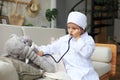 Adorable child dressed as doctor playing with toy elephant, checking its breath with stethoscope Royalty Free Stock Photo