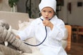 Adorable child dressed as doctor playing with toy elephant, checking its breath with stethoscope Royalty Free Stock Photo