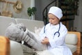 Adorable child dressed as doctor playing with toy elephant, checking its breath with stethoscope Royalty Free Stock Photo