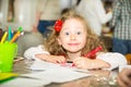 Adorable child girl drawing with colorful pencils in nursery room. Kid in kindergarten in Montessori preschool class.