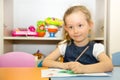 Adorable child girl draws a brush and paints in nursery room. Kid in kindergarten in Montessori preschool class. Royalty Free Stock Photo