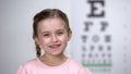 Adorable child girl laughing after vision test on eye chart, healthy sight