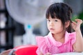 Adorable child girl sitting and make thinking face. Kid 4 year old wearing pink shirt and polka dots pattern. Royalty Free Stock Photo