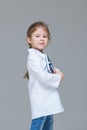 Adorable child girl uniformed as doctor is holding medical record isolated on grey background