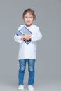 Adorable child girl uniformed as doctor is holding medical record isolated on grey background