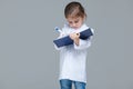 Adorable child girl uniformed as doctor is writing medical record on grey background