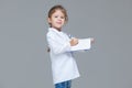 Adorable child girl uniformed as doctor is writing medical record on grey background