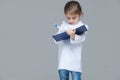 Adorable child girl uniformed as doctor is writing medical record on grey background