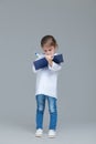 Adorable child girl uniformed as doctor is writing medical record isolated on grey background