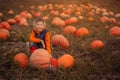 Adorable child having fun with pumpkin on pumpkinpatch on farm.