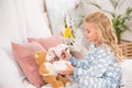Adorable child in pajamas feeding soft toys