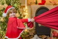 Adorable child play Santa at home. Santa helper with a huge bag. Family holiday. Little Santa huge bag run to delivery Royalty Free Stock Photo