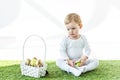 Child sitting on green grass near yellow and golden Easter eggs isolated on white Royalty Free Stock Photo