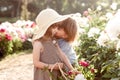 Adorable children boy and girl kiss in a peonies garden