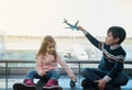 Adorable children, boy and little girl playing with toys planes sitting on the floor by the panoramic windows overlooking the Royalty Free Stock Photo