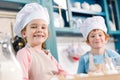 adorable children in chef hats and aprons smiling at camera while cooking together Royalty Free Stock Photo