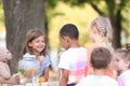 Adorable children waiting in queue for natural lemonade near stand in park