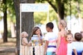 Adorable children waiting in queue for natural lemonade near stand in park