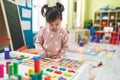 Adorable chinese girl playing with maths puzzle game standing at kindergarten