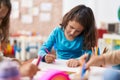 Adorable chinese girl preschool student sitting on table drawing on paper at classroom Royalty Free Stock Photo