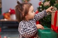 Adorable chinese toddler decorating christmas tree at home