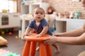 Adorable chinese toddler leaning on stool standing at kindergarten