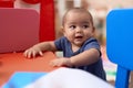 Adorable chinese toddler leaning on table standing at kindergarten