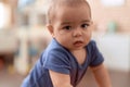 Adorable chinese toddler standing with serious expression at home