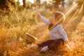 Adorable chubby little baby boy sitting in the grass and reaching into the Bush on the sunset sunlight Royalty Free Stock Photo