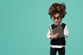 Adorable clever child reading textbook in turquoise studio Royalty Free Stock Photo