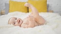 Adorable, confident baby, happily smiling, lying on bedroom bed, enjoying funny morning relaxation indoor at home