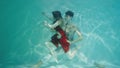 Couple dancing modern choreography underwater. Woman in red costume and man with halfnaked torso gracefully moves in