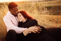 Adorable couple lay at the field, attractive husband gently hug adorable wife, overjoyed woman smiling, happy family