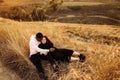 Adorable couple lay at the field, attractive husband gently hug adorable wife, overjoyed woman smiling, happy family