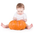 Adorable curious baby girl playing with big pumpkin