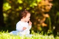 Adorable cute baby girl sitting on green meadow and eating the pastry. Royalty Free Stock Photo