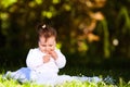 Adorable cute baby girl sitting on green meadow and eating the pastry. Royalty Free Stock Photo