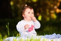 Adorable cute baby girl sitting on green meadow and eating the pastry. Royalty Free Stock Photo