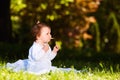 Adorable cute baby girl sitting on green meadow and eating the pastry. Royalty Free Stock Photo