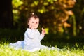 Adorable cute baby girl sitting on green meadow and eating the pastry. Royalty Free Stock Photo