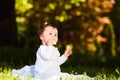 Adorable cute baby girl sitting on green meadow and eating the pastry. Royalty Free Stock Photo