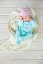 Adorable cute baby girl sleeping in white basket on wooden floor