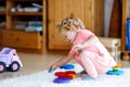 Adorable cute beautiful little baby girl playing with educational colorful wooden rainboy toy pyramid Royalty Free Stock Photo