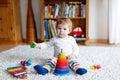 Adorable cute beautiful little baby girl playing with educational colorful wooden rainboy toy pyramid Royalty Free Stock Photo