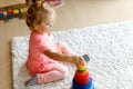 Adorable cute beautiful little baby girl playing with educational colorful wooden rainboy toy pyramid Royalty Free Stock Photo