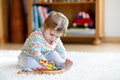 Adorable cute beautiful little baby girl playing with educational wooden music toys at home or nursery. Toddler with