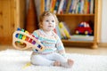 Adorable cute beautiful little baby girl playing with educational wooden music toys at home or nursery. Toddler with Royalty Free Stock Photo